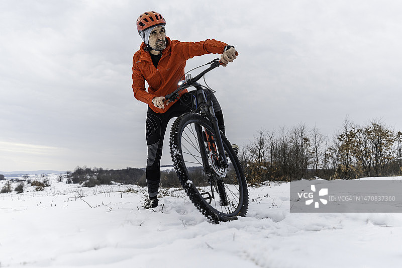 冬季户外锻炼：男子在雪中骑自行车图片素材