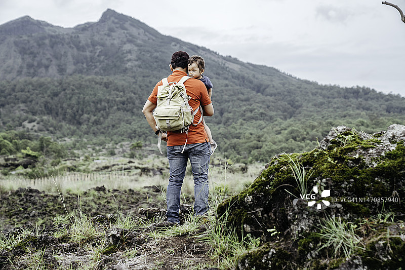 亚洲男人抱着他的孩子看着巴图尔山图片素材