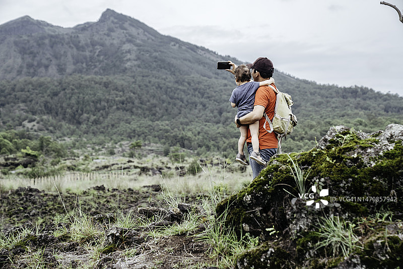 亚洲男人抱着他的孩子看着巴图尔山图片素材