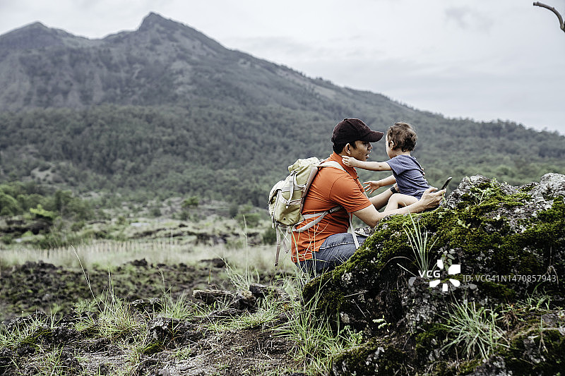 亚洲男人抱着他的孩子看着巴图尔山图片素材