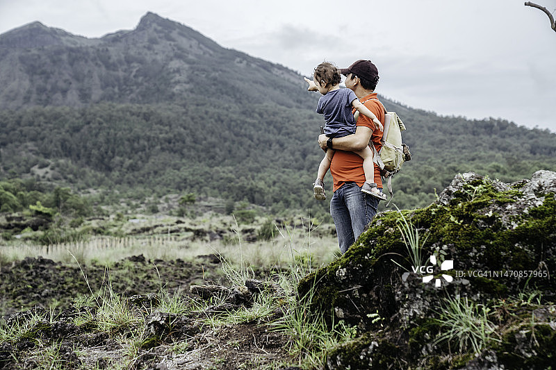 亚洲男人抱着他的孩子看着巴图尔山图片素材