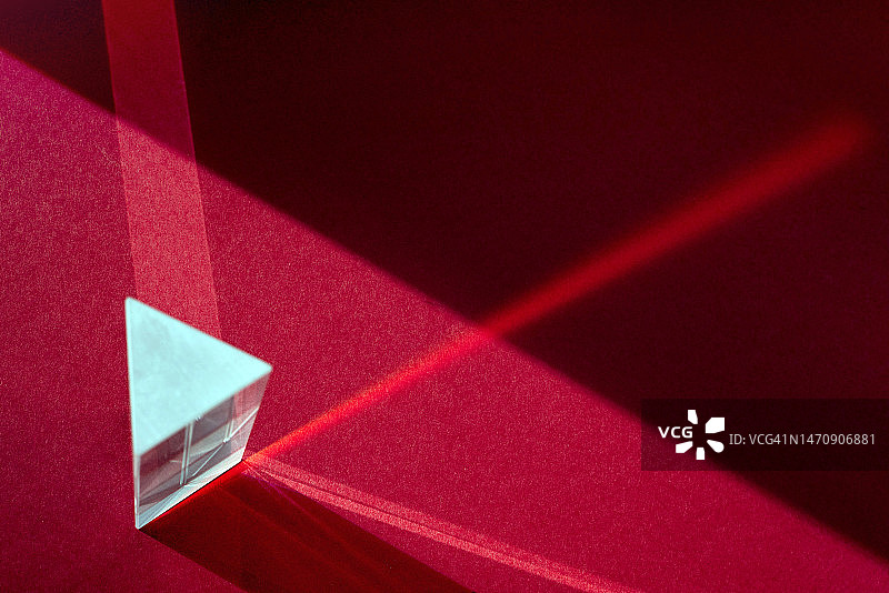 穿过玻璃棱镜的光线，以深红色栗色为背景图片素材