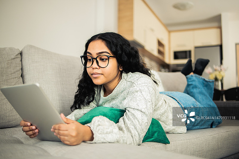 在沙发上使用平板电脑的漂亮女孩图片素材