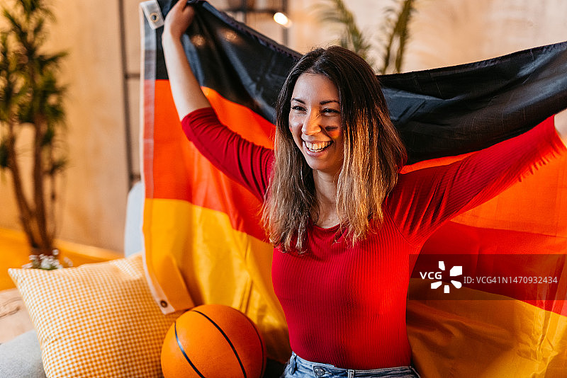 年轻女人在家观看篮球比赛并为德国队加油图片素材