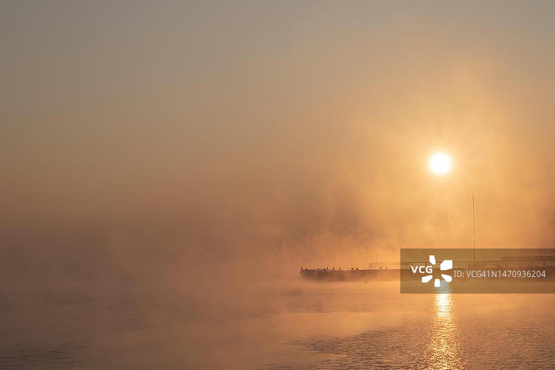 泻湖上的冬季日出：美丽日出与上升的雾气，波兰雷布尼克图片素材
