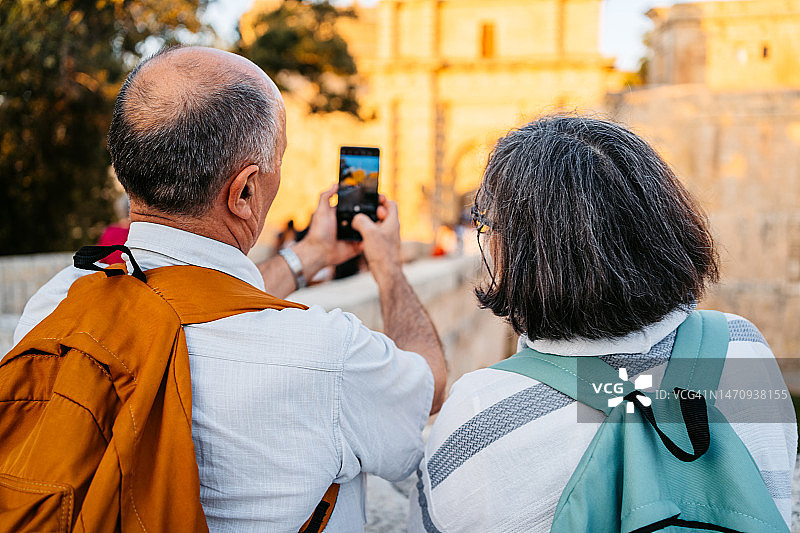 老年游客夫妇在马耳他姆迪纳门前拍照图片素材