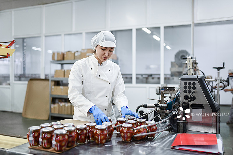 食品加工厂女工操作机器腌制辣椒罐头图片素材