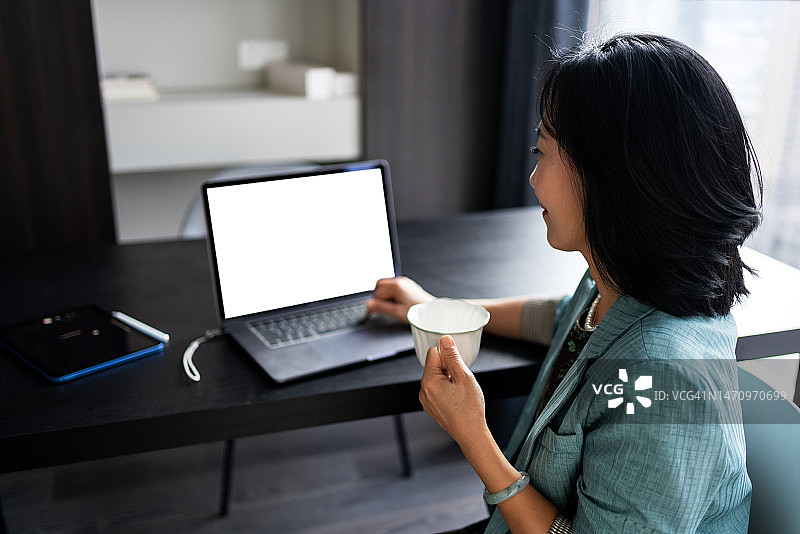 年轻女商人在工作时查看笔记本电脑上的数据图片素材