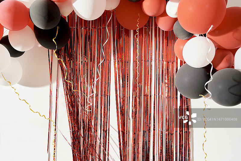 白色墙壁上装饰的红色、黑色和白色气球及红色彩带图片素材