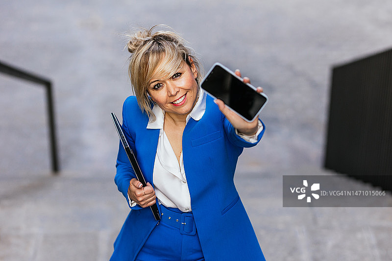 女商人在城市楼梯上行走时展示手机屏幕图片素材