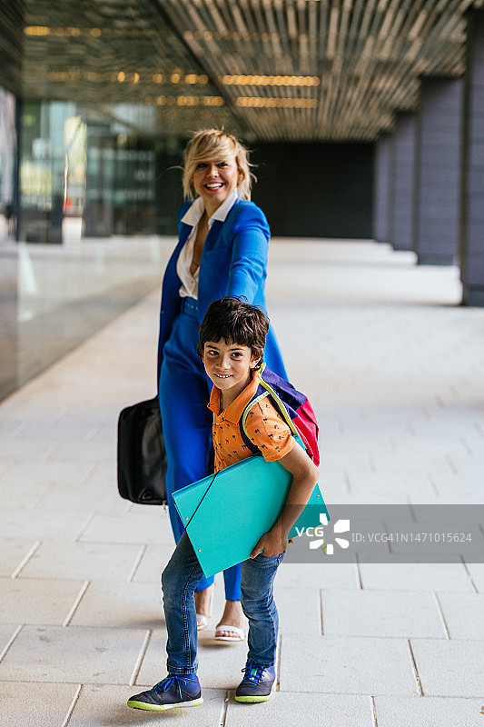 商务女人和儿子手牵手走在工作场所外图片素材