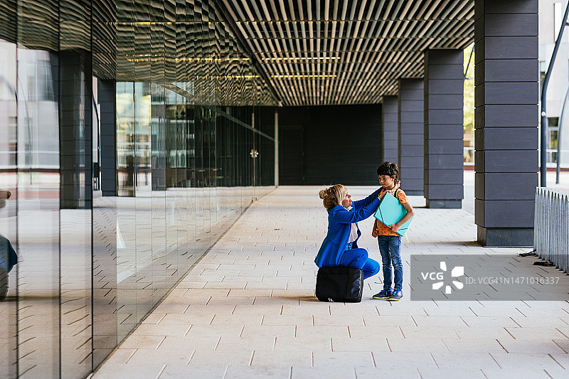 办公室外女商人为儿子整理衬衫领子图片素材