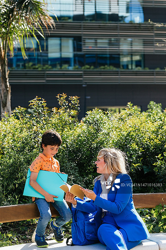 阳光明媚的日子，母亲和孩子坐在公园的长椅上图片素材