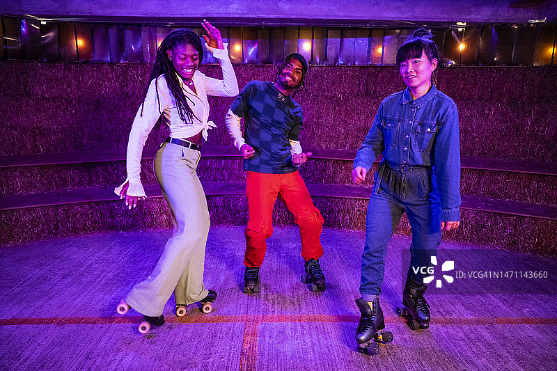 在霓虹灯下一起跳舞的亚洲和黑人轮滑舞者图片素材