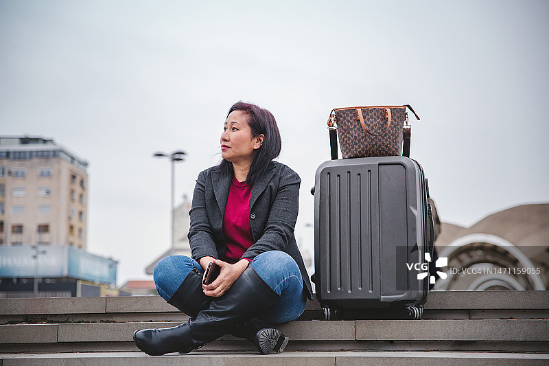 坐在楼梯上拿着手提箱的女人图片素材
