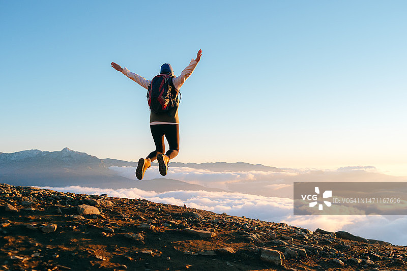 女游客在日落时分于山中跳跃图片素材