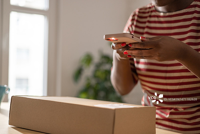 黑人女性用智能手机扫描包裹上的二维码图片素材