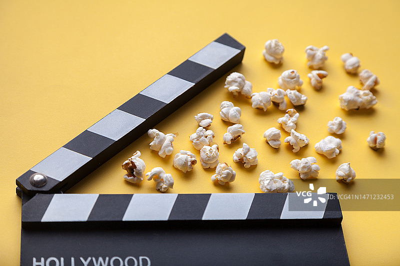 黄色背景上的电影拍板和爆米花图片素材