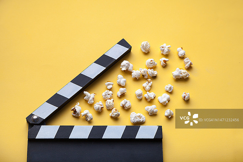 黄色背景上的电影拍板和爆米花图片素材