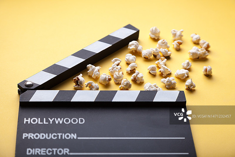 黄色背景上的电影拍板和爆米花图片素材