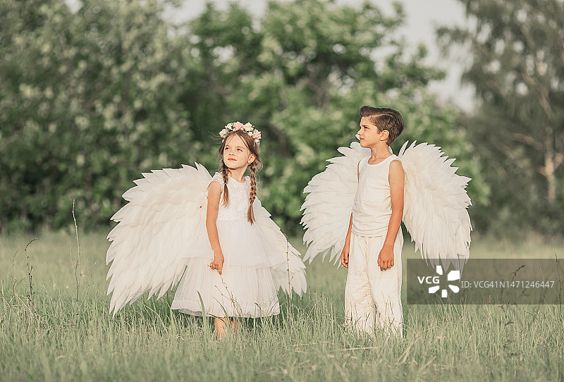 绿草地上长着白色翅膀的两个天使图片素材