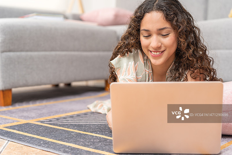 充满爱意的年轻女子与爱人视频通话，躺在客厅的地毯上图片素材