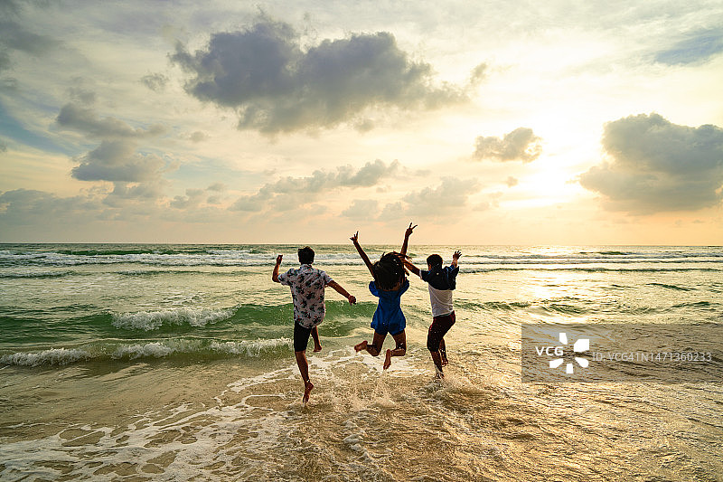 在海滩度假时跳跃的快乐年轻人图片素材