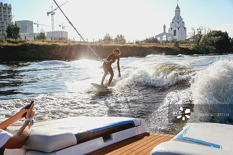 中年女冲浪者在阳光明媚的夏日早晨，在快艇后方玩尾波滑水图片素材