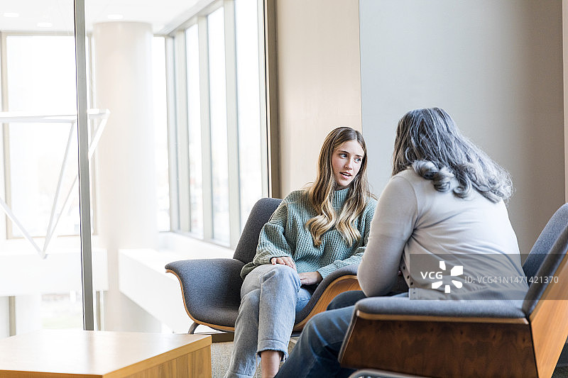 年轻女人与女咨询师交流时看向别处图片素材
