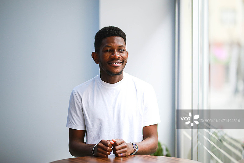 穿着白色T恤的年轻黑人男子在室内大笑的肖像图片素材