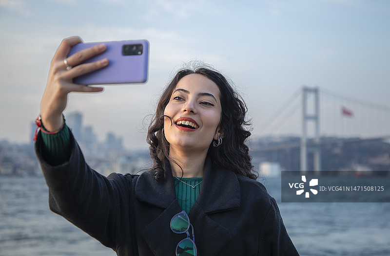 戴眼镜在博斯普鲁斯海峡自拍的年轻漂亮黑发女子图片素材