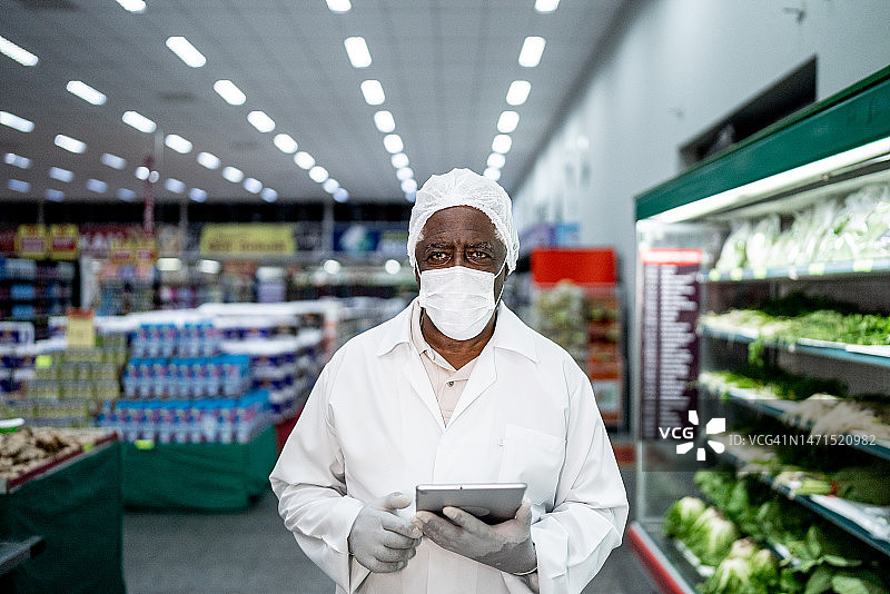 在超市使用平板电脑的年长检查员肖像图片素材