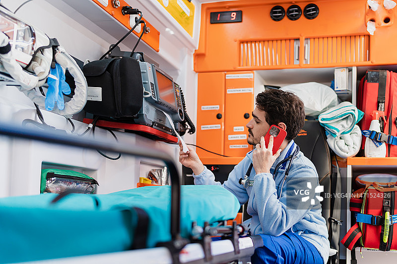 医生看着心电图，同时在打电话图片素材