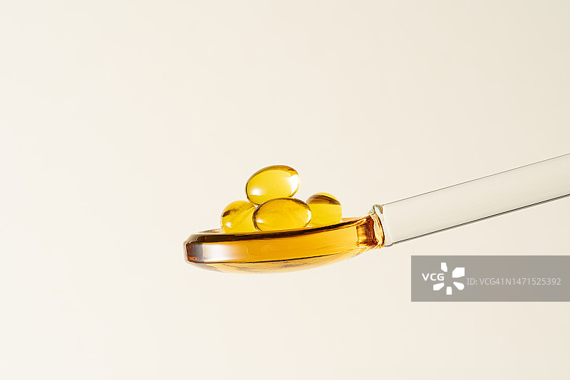 玻璃勺中的黄色软胶囊图片素材