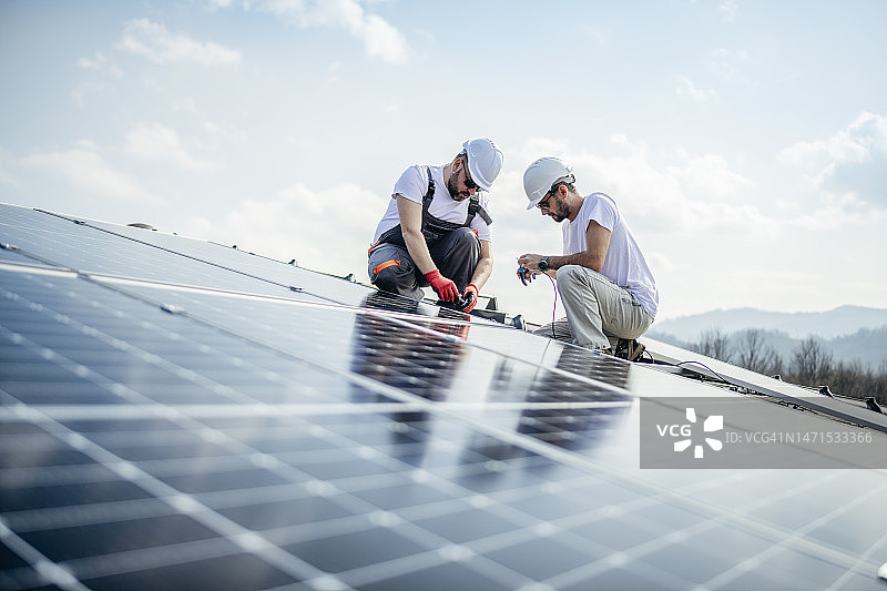 两名工人在屋顶安装太阳能电池板图片素材