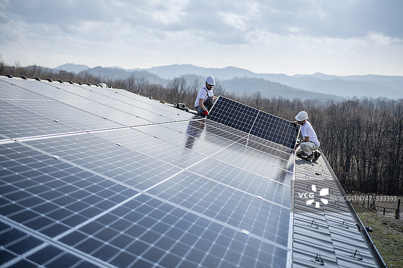 两名工人在屋顶安装太阳能电池板图片素材