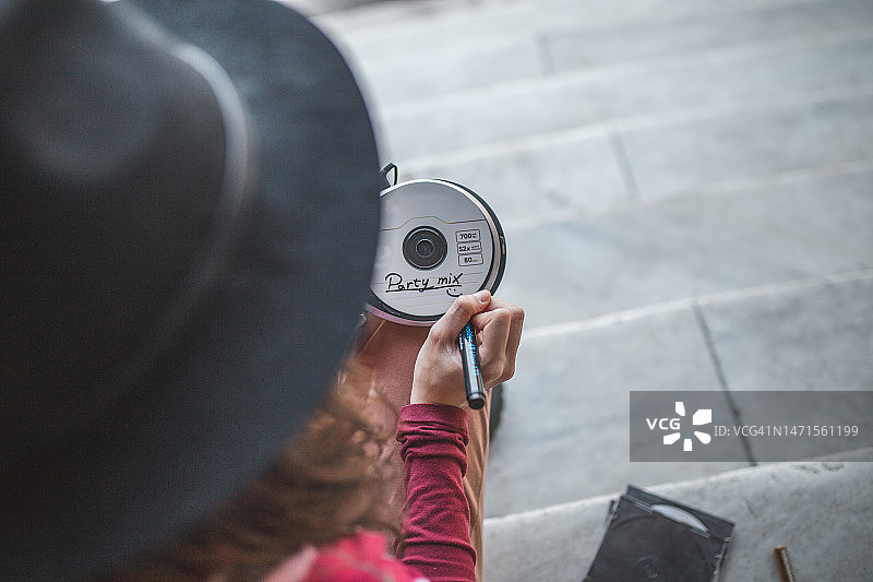 一位女士用毡尖笔在CD上写名字的背面视角图片素材