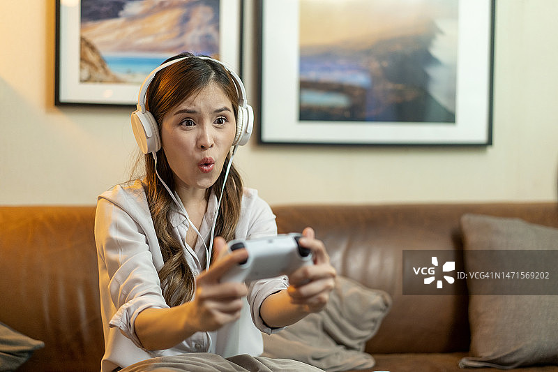 年轻女人在家玩电子游戏，乐在其中图片素材