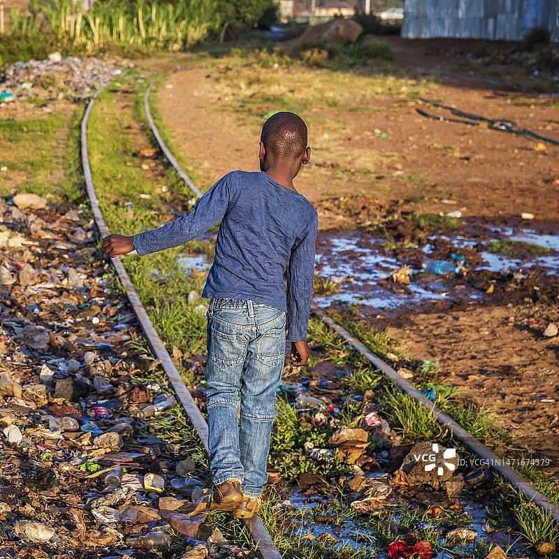 在肯尼亚基贝拉贫民窟铁轨上行走的非洲小男孩图片素材