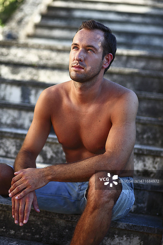 男人赤膊坐在旧楼梯上图片素材