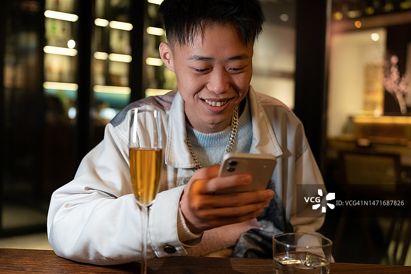在酒吧里用手机发信息的年轻男子图片素材