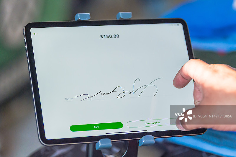 在数字平板电脑上签名以支付信用卡费用的人图片素材