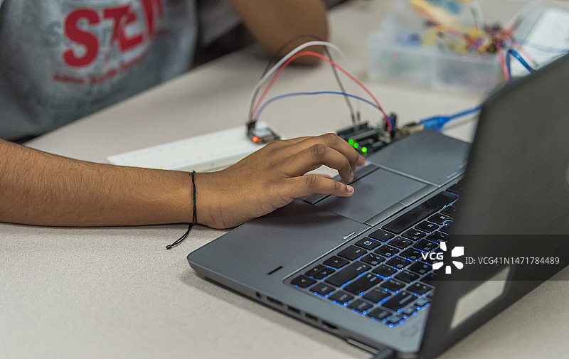 女高中生在计算机科学课上使用控制板、电路和电脑进行STEM项目图片素材