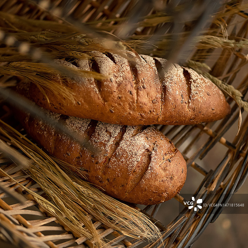 多种谷物面包与麦穗，置于柳条筐中的新鲜糕点图片素材