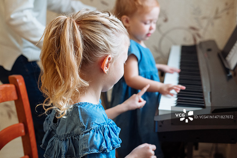 两个金发小女孩正在学习弹钢琴。从小培养创意爱好图片素材