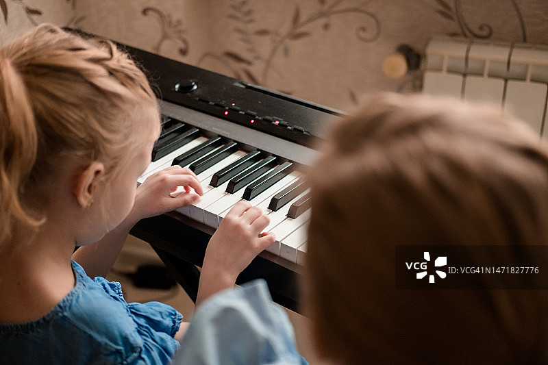 妈妈教女儿弹钢琴，俯视角度拍摄，孩子和女人的手在钢琴键盘上特写图片素材