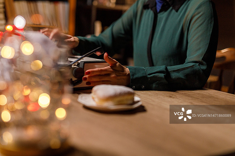 在打字机上工作的女人，旁边有圣诞灯和心形零食图片素材