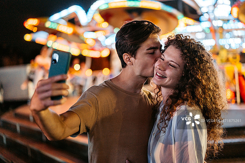 游乐园里自拍的年轻夫妇图片素材