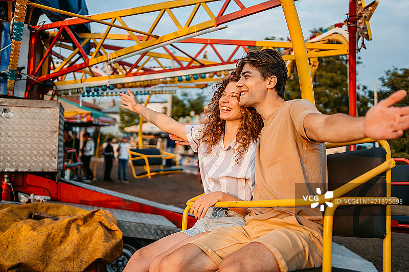 年轻夫妇在游乐园乘坐旋转秋千图片素材