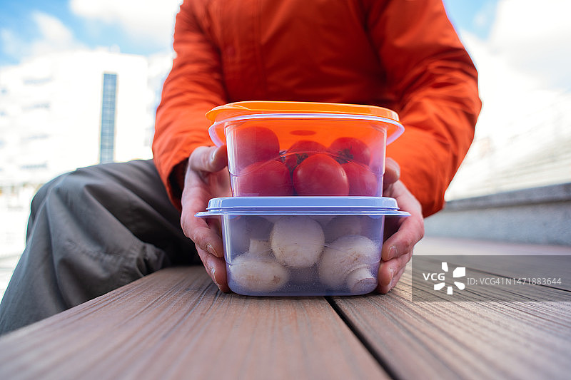 男子手持蔬菜和鹰嘴豆泥午餐盒图片素材